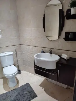 a bathroom with a toilet and a sink and a mirror at Chaleureux Appartement à 1 min à pied de la Mosquée Hassan II in Casablanca