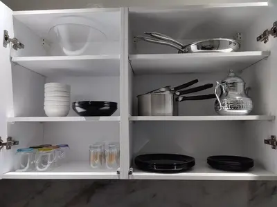 a white cabinet filled with dishes and plates at Chaleureux Appartement à 1 min à pied de la Mosquée Hassan II in Casablanca