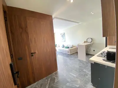 a kitchen with a wooden door and a living room at NEW modern 1 BR, 1min fr tramway in Casablanca