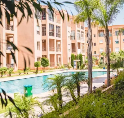 a swimming pool with palm trees in front of a building at Ricoflores PALM in O Ben Slimane