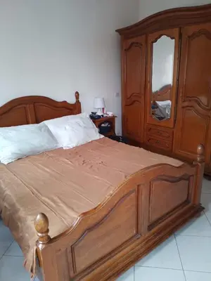 a bedroom with a wooden bed with a dresser and a mirror at Bel appartement quartier Bourgogne in Casablanca