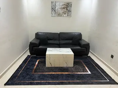 a black leather couch with a coffee table in a room at magnifique appartement à rabat proche de la mer in Rabat