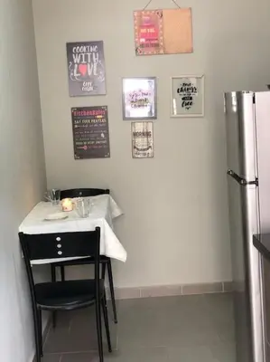 a small table with a black chair and a refrigerator at Charmant studio lumineux Casablanca in Bouskoura