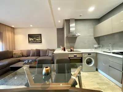 a kitchen and living room with a glass table at Faubourgs Anfa Top Floor By AppartAli in Casablanca