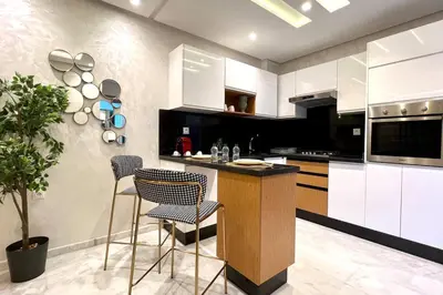a kitchen with white cabinets and a island with chairs at The Suite of Artists - Central - By AppartAli in Casablanca