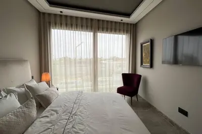 a bedroom with a bed and a window and a chair at Royal Suite by the Ocean - By Appartali in Casablanca