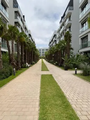a brick walkway with palm trees in front of a building at La Corniche- Fab Design Ocean - By AppartAli in Casablanca