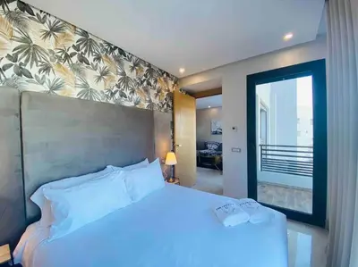 a bedroom with a white bed and a large window at Mogador Presidential Terrace - By AppartAli in Casablanca