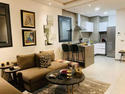 a living room with a couch and a table and a kitchen at Faubourgs D Anfa Suite - By AppartAli in Casablanca