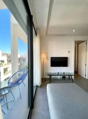 a living room with a television and a table and chairs at Racine Zara Street - By AppartAli in Casablanca