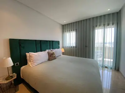 a bedroom with a large bed with a green headboard at Maarif Top Floor - 2 Bedrooms - By AppartAli in Casablanca