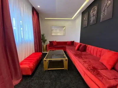 a living room with a red couch and a table at Corniche Casablanca - Red’s Neuf in Casablanca