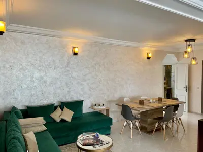 a living room with a green couch and a table at Bel appartement avec une belle vue sur la grande mosquée Hassan II et la mer in Casablanca