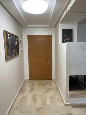 a hallway with a wooden door and paintings on the wall at Chic & cosy Flat Near Airport lockbox fast wifi in Nouaceur