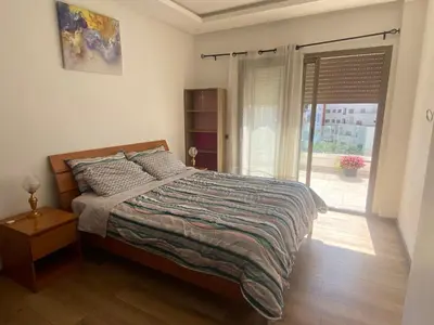 a bedroom with a bed and a large window at Beaulieu du Park commode et paisible in Mohammedia