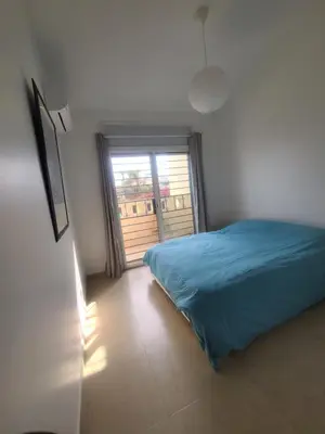 a bedroom with a blue bed and a window at Les Portes de l'Océan avec piscine uniquement l'été in El Harhoura