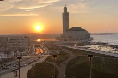 a view of a city with a clock tower at sunset at Marina - Sea & Mosque View - By AppartAli in Casablanca