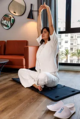 a woman sitting on a yoga mat with her arms in the air at Kaan Casablanca in Casablanca