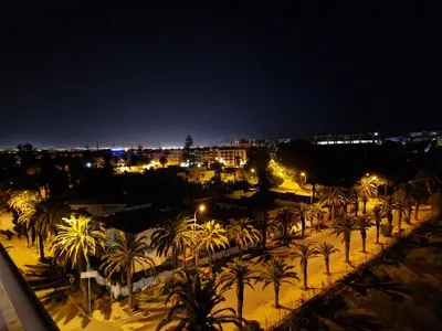 a view of a city at night with palm trees at luxe appartement met zeezicht en zwembad Mohammedia Parc in Mohammedia