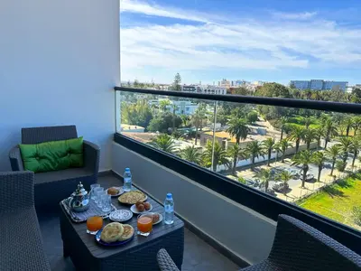 a balcony with a table with food and a view of a city at luxe appartement met zeezicht en zwembad Mohammedia Parc in Mohammedia