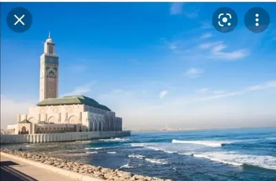 a large building with a clock tower next to the ocean at Splendid appartament a 3 Min de la mer et de la mosquée hassan 2 in Casablanca