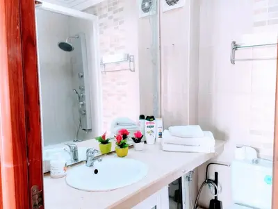 a white bathroom with a sink and a mirror at Splendid appartament a 3 Min de la mer et de la mosquée hassan 2 in Casablanca