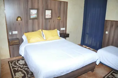 a bedroom with a large bed with white sheets and yellow pillows at Gite Nadia in Casablanca