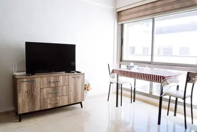 a living room with a tv on a dresser and a table with chairs at Cozy New Studio in Mohammedia in Mohammedia