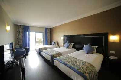 a hotel room with three beds and a television at Hotel Suisse in Casablanca
