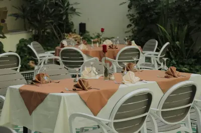 a table with white chairs and tables with brown napkins at Hotel Suisse in Casablanca