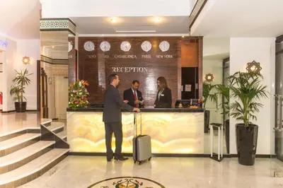 a man with a suitcase standing in a lobby at Hotel Toubkal in Casablanca