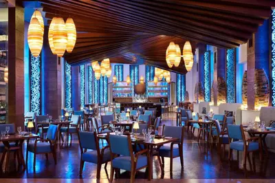 a dining room with tables and chairs and chandeliers at Mazagan Beach & Golf Resort in El Jadida