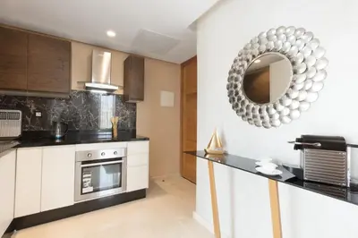 a kitchen with white cabinets and a mirror on the wall at ZEN Suites Hotel Massira in Casablanca